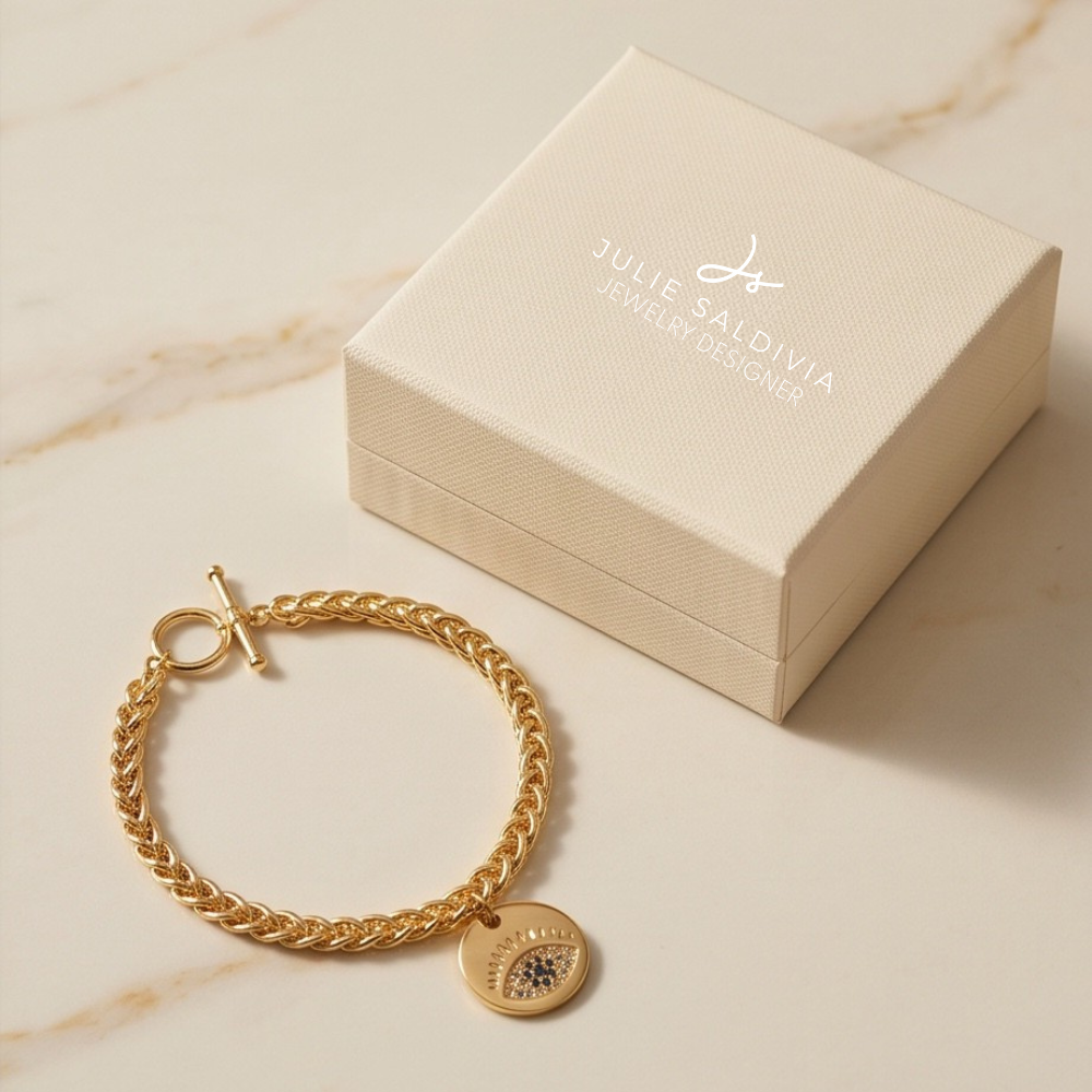Gold chain bracelet with round evil eye charm on marble background